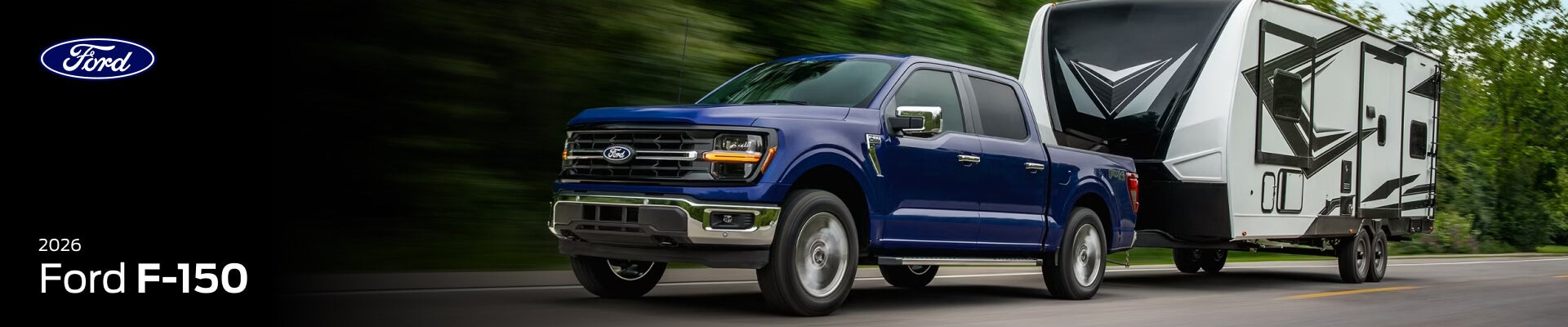 A front three quarter view of a blue 2026 Ford F-150 towing a camper trailer down a forest highway.
